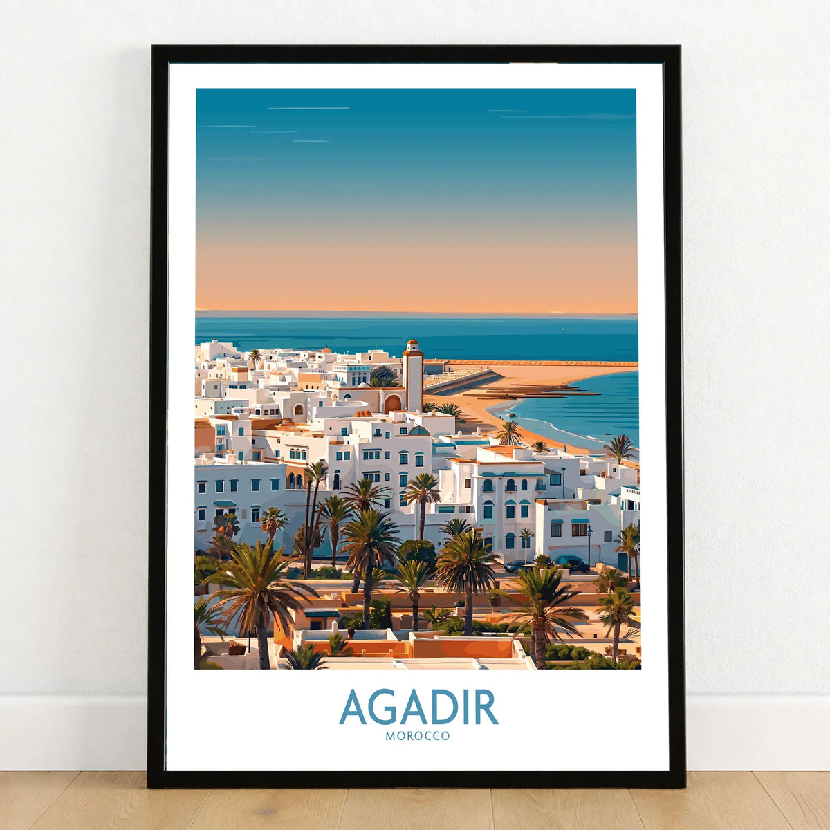 Agadir Morocco Wall Art – Mediterranean Canvas Art in a black wooden frame leaning against a white wall on a light wooden floor