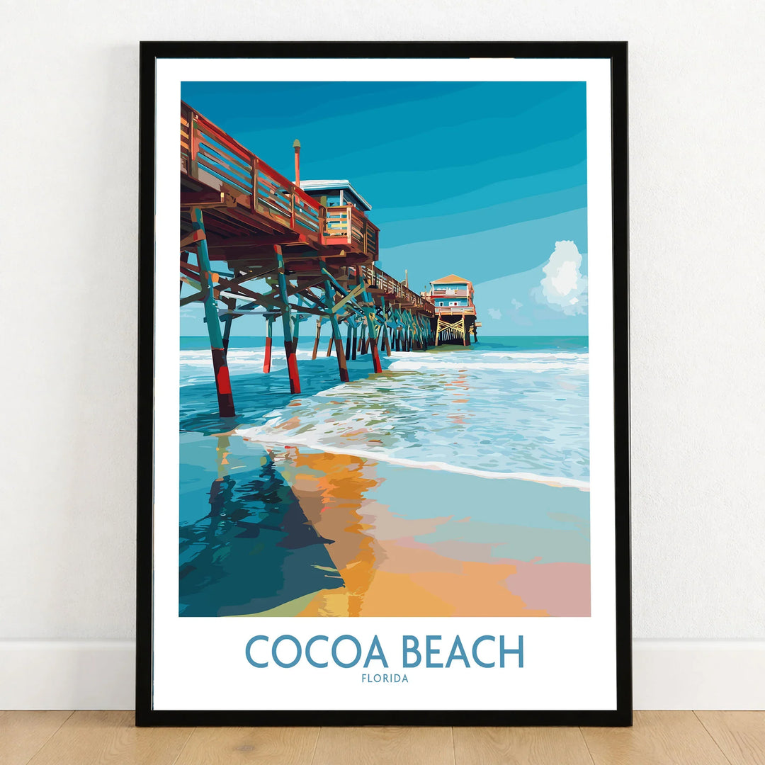Cocoa Beach Pier Poster - Florida Beach Travel Decor in a black wooden frame leaning against a white wall on a light wooden floor