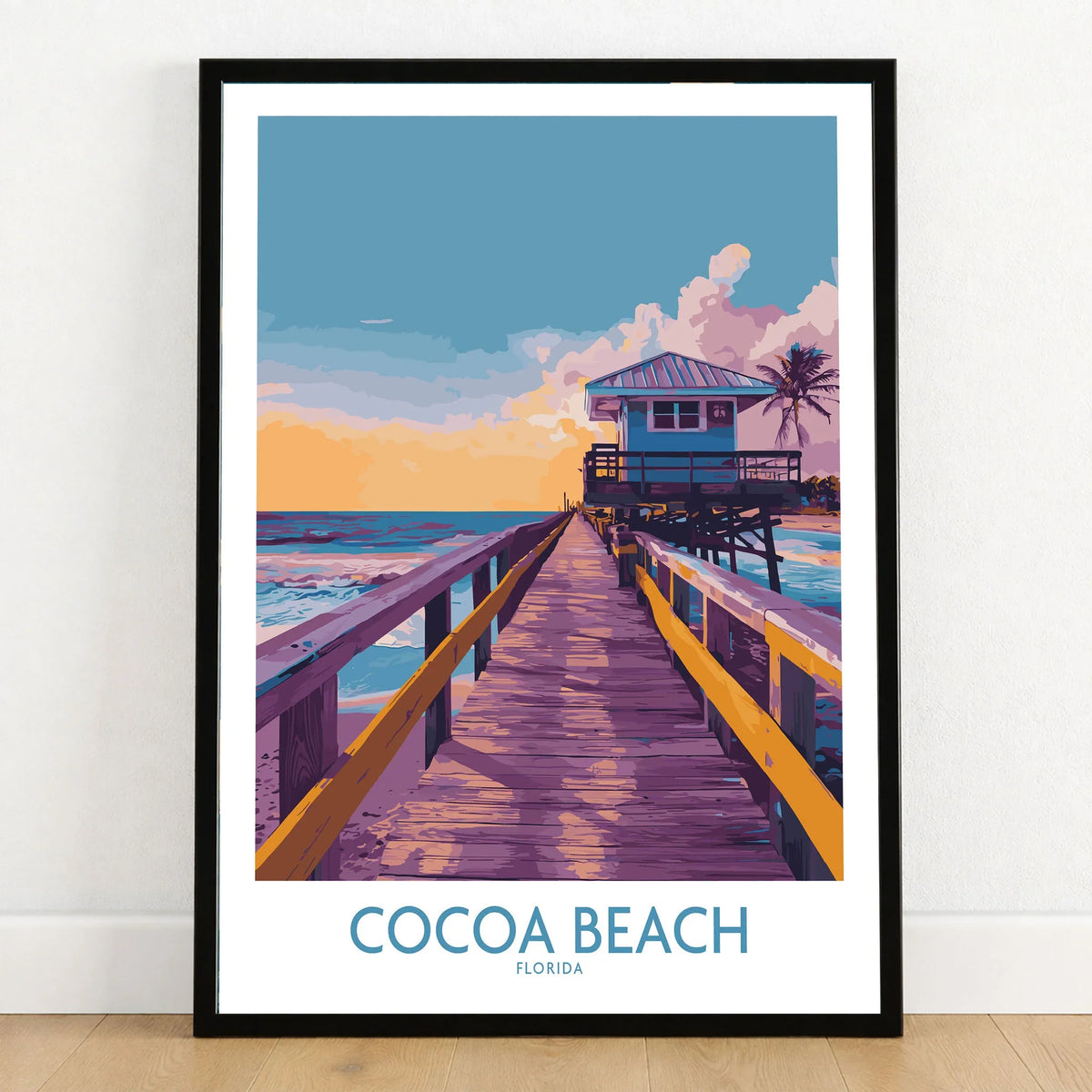 Cocoa Beach Florida Wooden Pier Poster - Golden Hour Sunset Decor in a black wooden frame leaning against a white wall on a light wooden floor