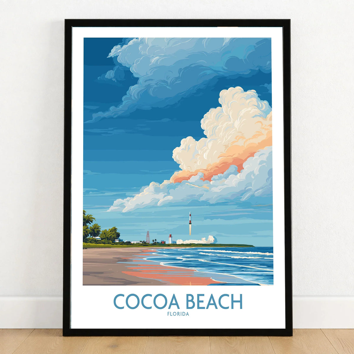 Cocoa Beach Kennedy Space Center Poster - Florida Wall Art Decor in a black wooden frame leaning against a white wall on a light wooden floor