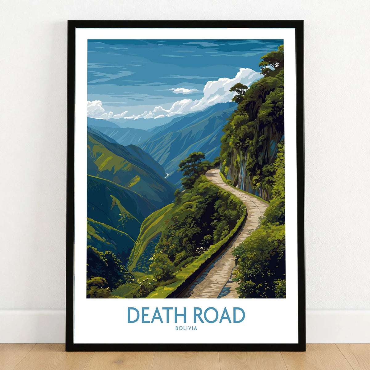 Death Road Bolivia Art Print | Yungas Road Poster in a black wooden frame leaning against a white wall on a light wooden floor