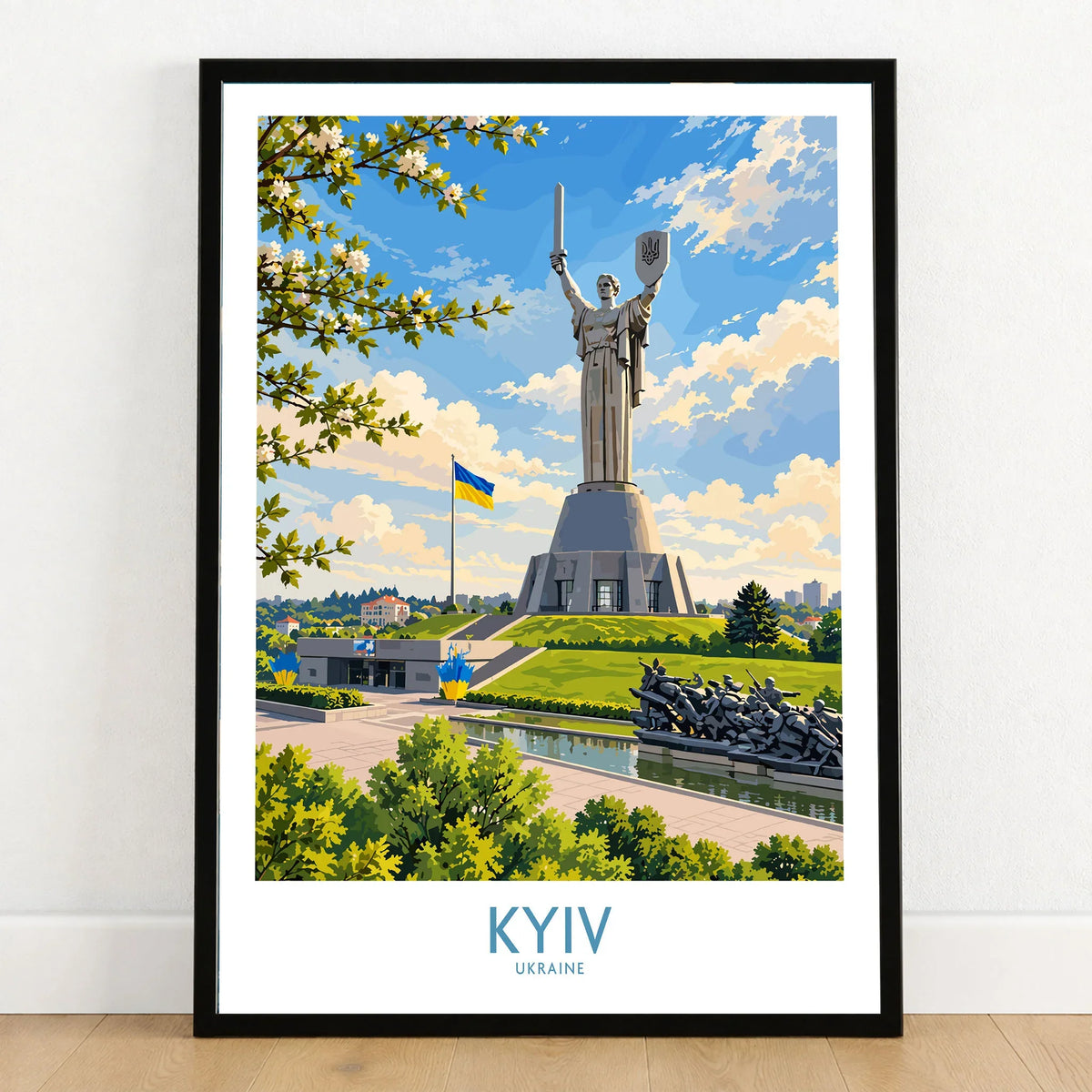Kyiv Ukraine Spring Blossom Wall Art — the Motherland Monument under spring blossom with the Ukrainian flag flying, shown as art print in black frame on wooden floor