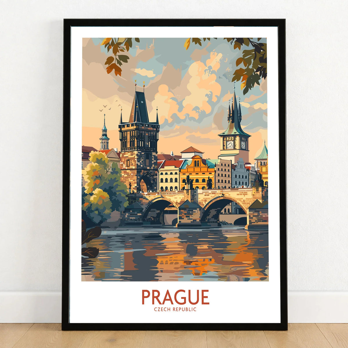 Prague Travel Poster in a black wooden frame leaning against a white wall on a light wooden floor