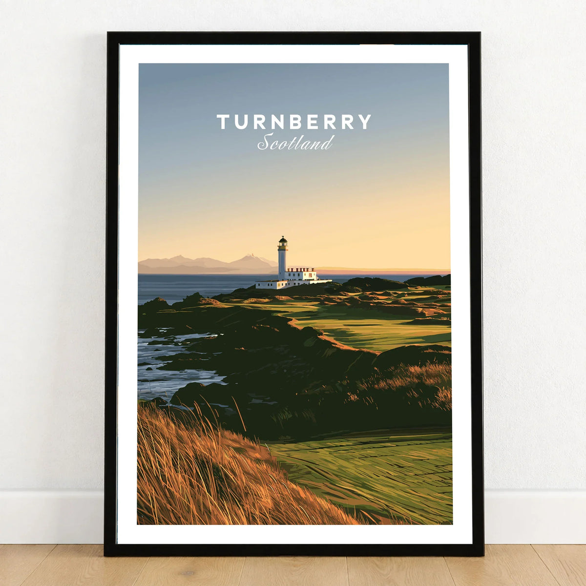 Turnberry Scotland Lighthouse Travel Poster — the Turnberry lighthouse above a rocky shore with the Arran hills beyond, shown as art print in black frame on wooden floor