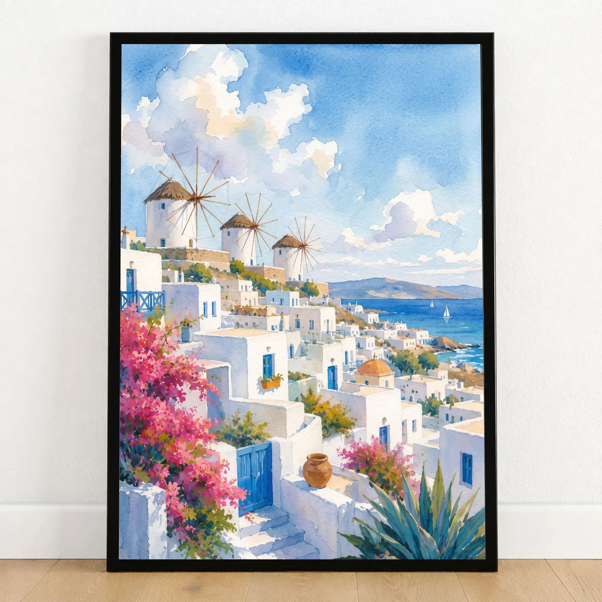 Mykonos windmills and white houses watercolour art print in a black frame on a wooden floor