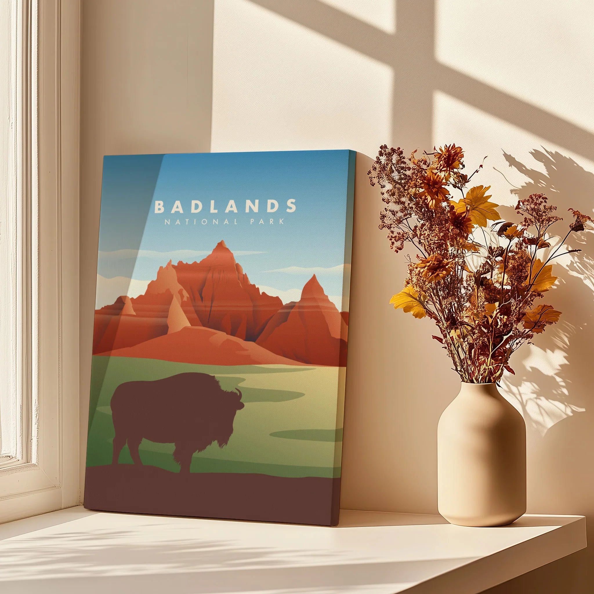 Badlands National Park canvas print with bison and mountains, beside a vase of dried flowers.