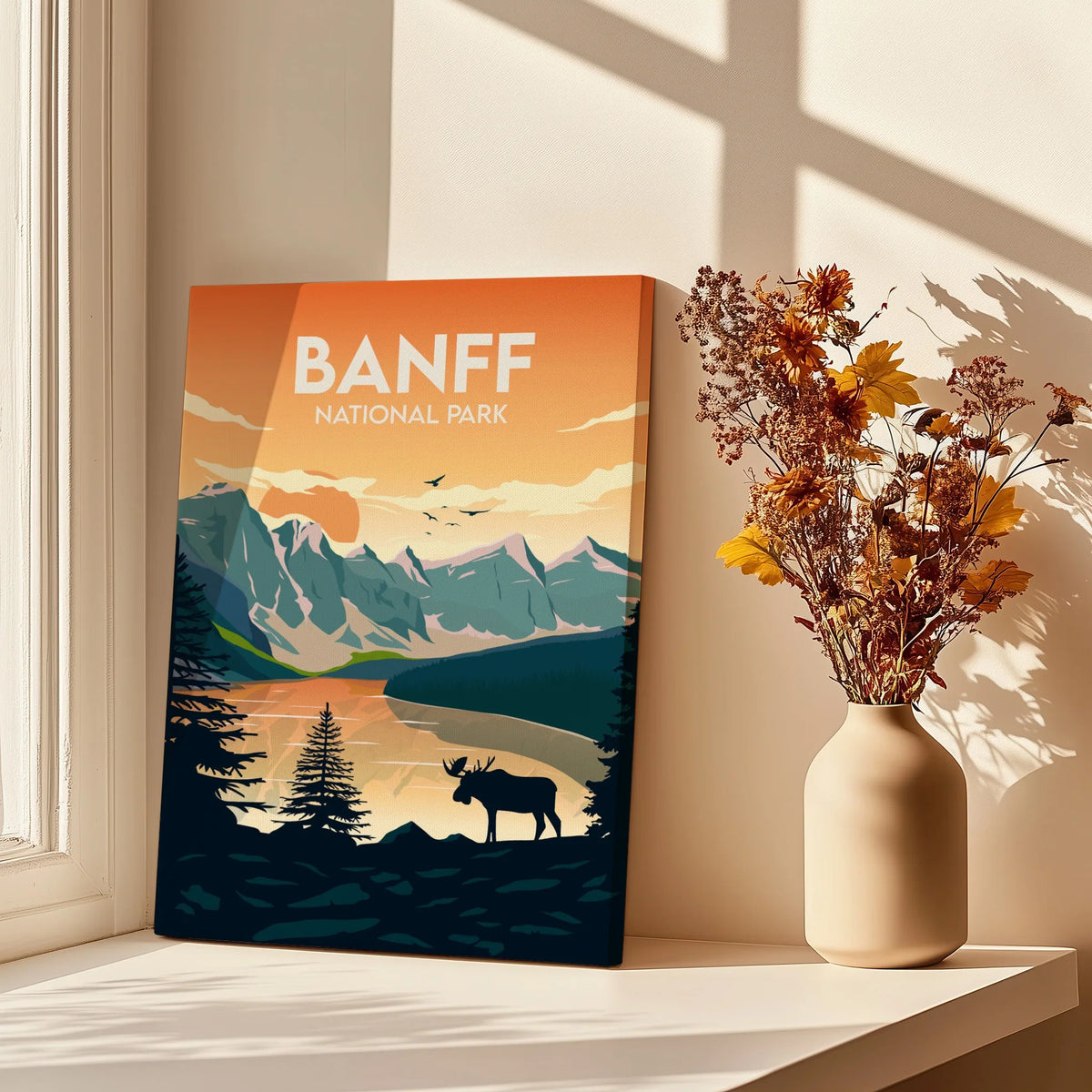 Banff National Park art print with mountain landscape and moose, beside vase with dried flowers