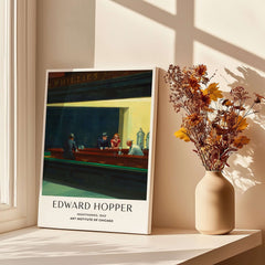 Edward Hopper Nighthawks 1942 Iconic Diner Art Print AIC Poster displayed by a window with flowers.