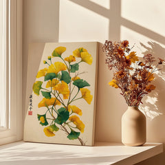 Ginkgo leaf canvas print with yellow flowers in a beige vase by a sunlit window.
