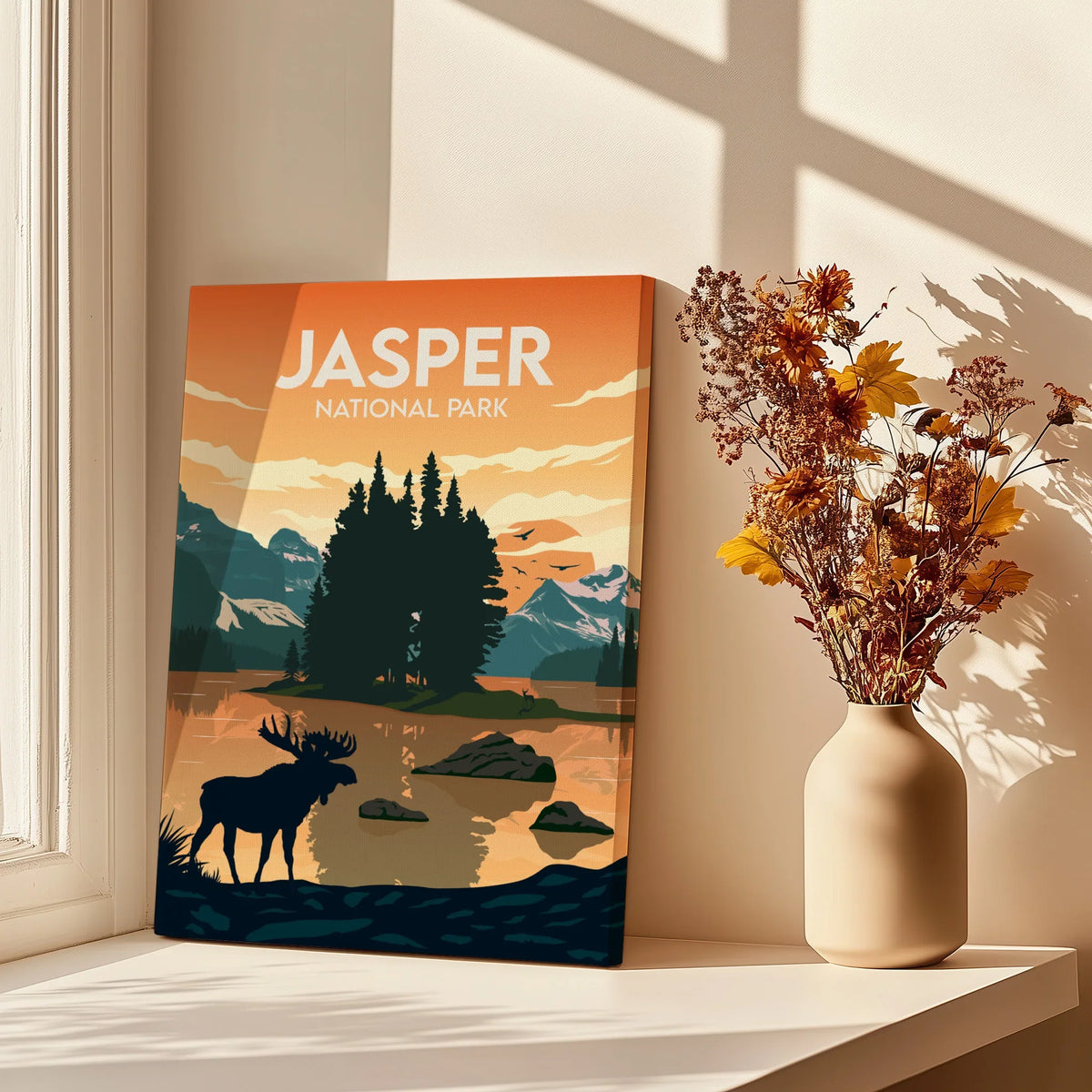 Jasper National Park print with moose, mountains, and lake on windowsill beside vase of flowers