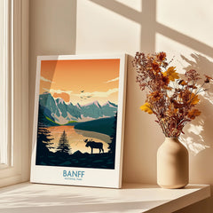 Banff National Park travel poster on a windowsill beside a vase of dried flowers in sunlight