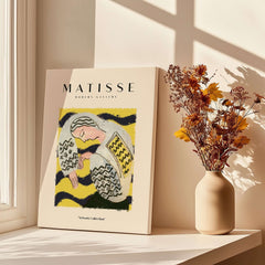 Matisse Art Prints - Resting Woman Patterned Blouse Yellow displayed on a table with a vase of flowers and sunlight.