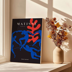 Matisse Art Prints - Dance Blue Figures Poster displayed on a table near flowers in a vase.
