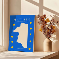 Matisse Art Prints -  Blue Abstract Profile with Yellow Dots Poster displayed on a windowsill with flowers.