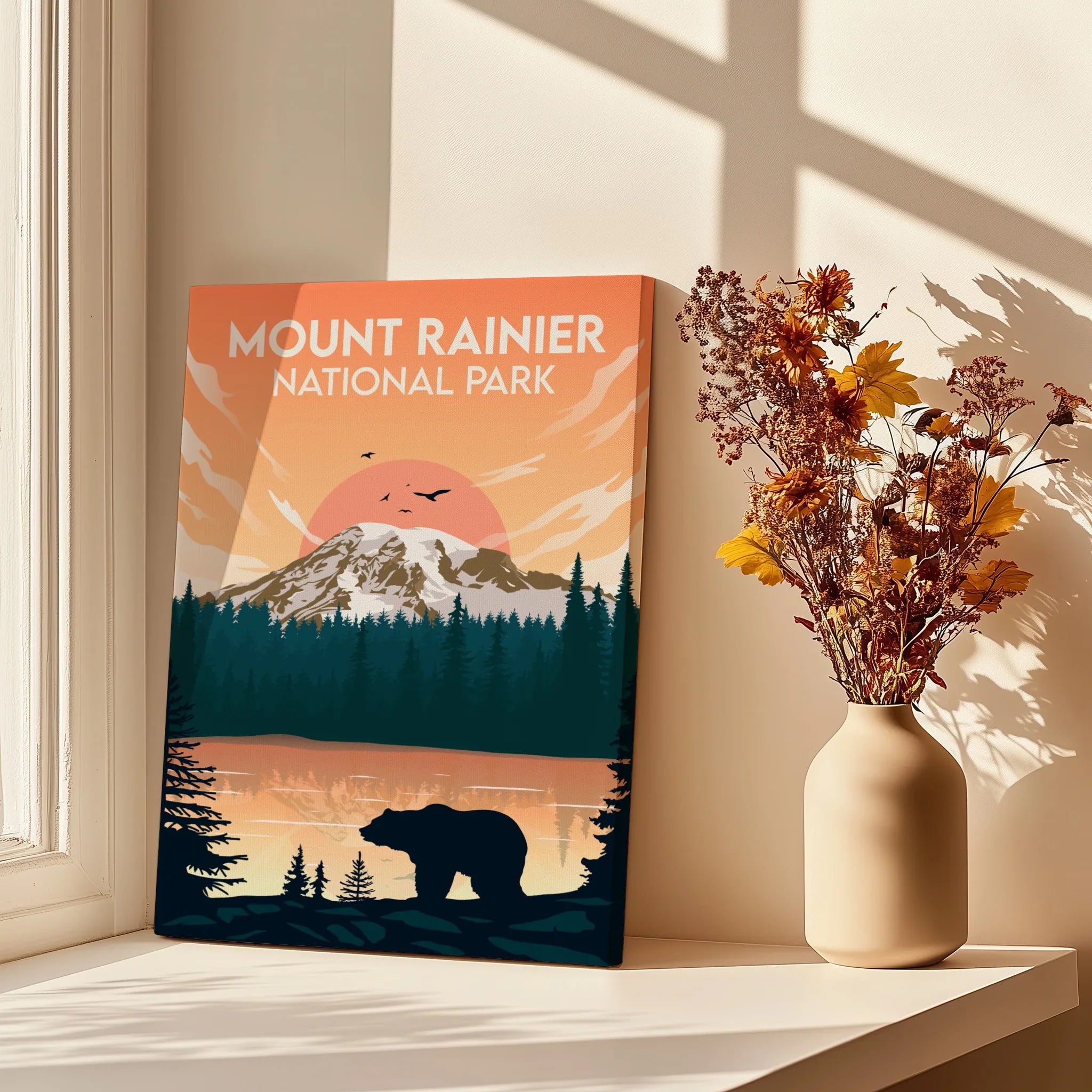 Mount Rainier National Park print with bear and sunset, next to vase of dried flowers on window ledge.