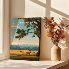Richmond Park travel poster print with deer and skyline, displayed on sunlit windowsill beside vase of dried flowers