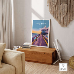 Cocoa Beach Boardwalk Print - Florida Sunset Wall Art displayed in a cozy interior setting, evoking coastal charm.