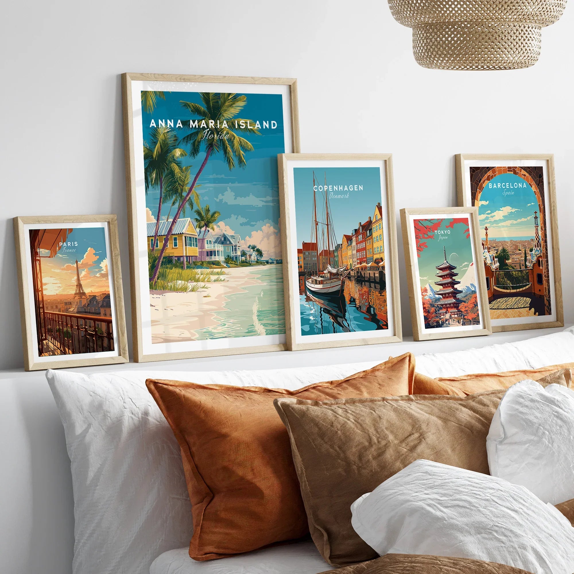 Five framed travel posters above a bed featuring Paris, Anna Maria Island, Copenhagen, Tokyo, and Barcelona.