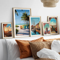 Framed travel art prints of Paris, Anna Maria Island, Copenhagen, Tokyo, and Barcelona above a bed