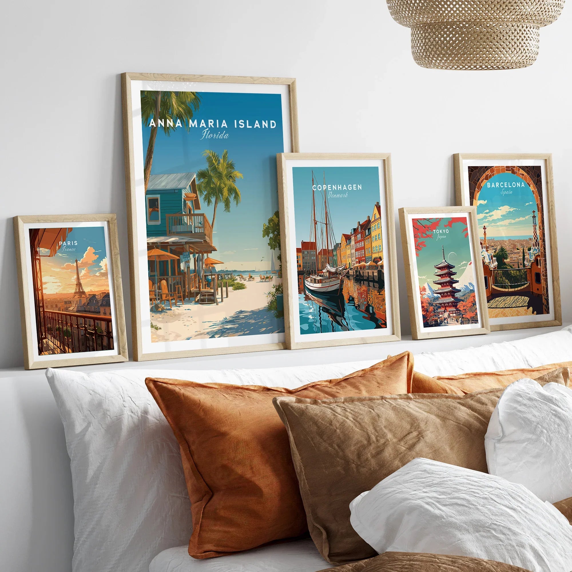 Travel poster wall art set in natural wood frames above bed, featuring Paris, Anna Maria Island, Copenhagen, Tokyo, and Barcelona prints