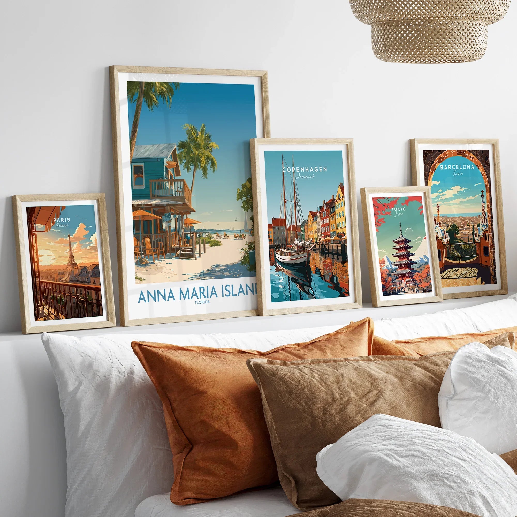Framed travel posters of Paris, Anna Maria Island, Copenhagen, Tokyo, and Barcelona above a bed.