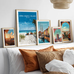 Framed travel posters of Paris, Anna Maria Island, Copenhagen, Tokyo, and Barcelona above a bed