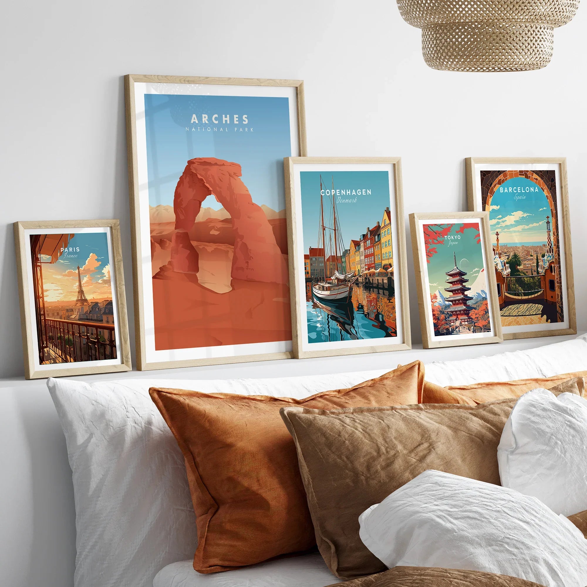 Set of five framed travel art prints above bed, featuring national park and city scenes