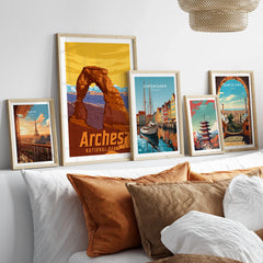 Framed travel art prints of Arches National Park, Paris, Copenhagen, Tokyo, and Barcelona above bed