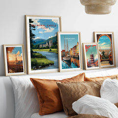Set of five framed travel art prints above a bed, featuring city and landscape scenes.