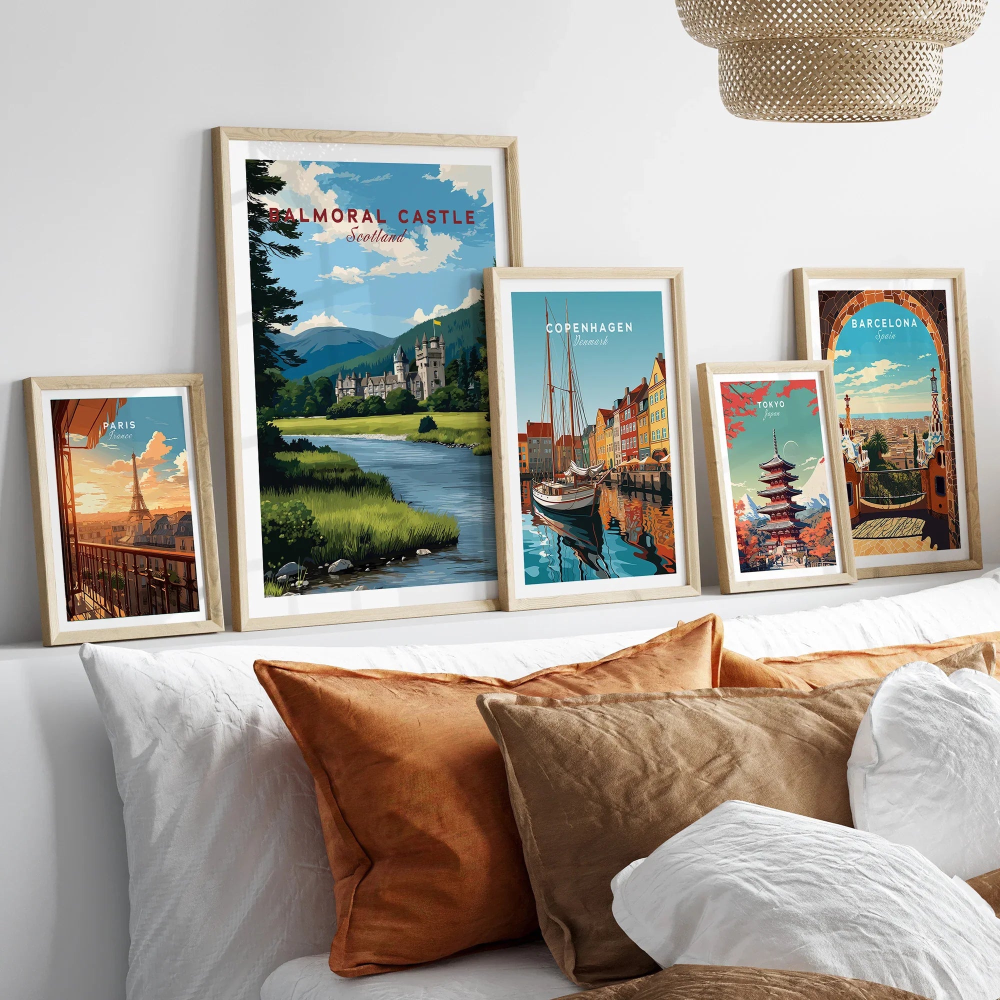 Set of five framed travel art prints above a bed, featuring city and landscape scenes.