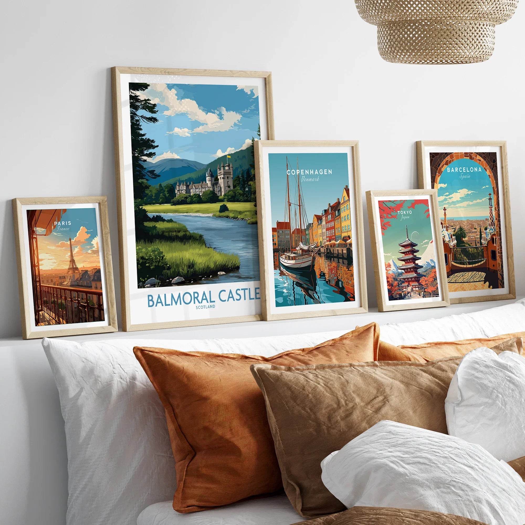 Framed travel city skyline art prints above bed with white and brown pillows.