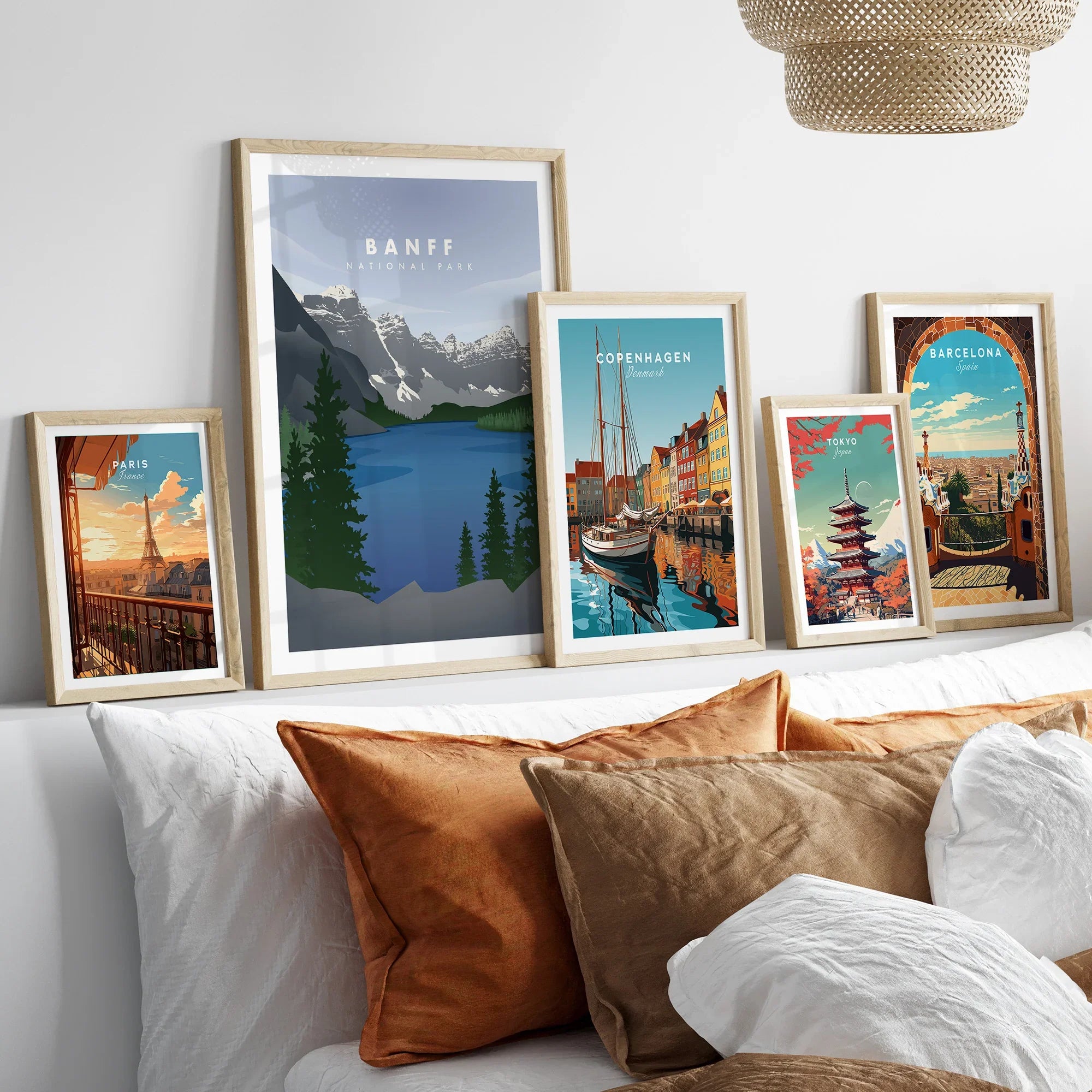 Five framed travel art prints of Banff, Paris, Copenhagen, Tokyo, and Barcelona above a bed.
