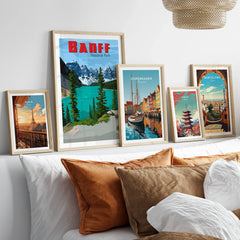 Framed travel posters of Banff, Paris, Copenhagen, Tokyo, and Barcelona above bed with pillows