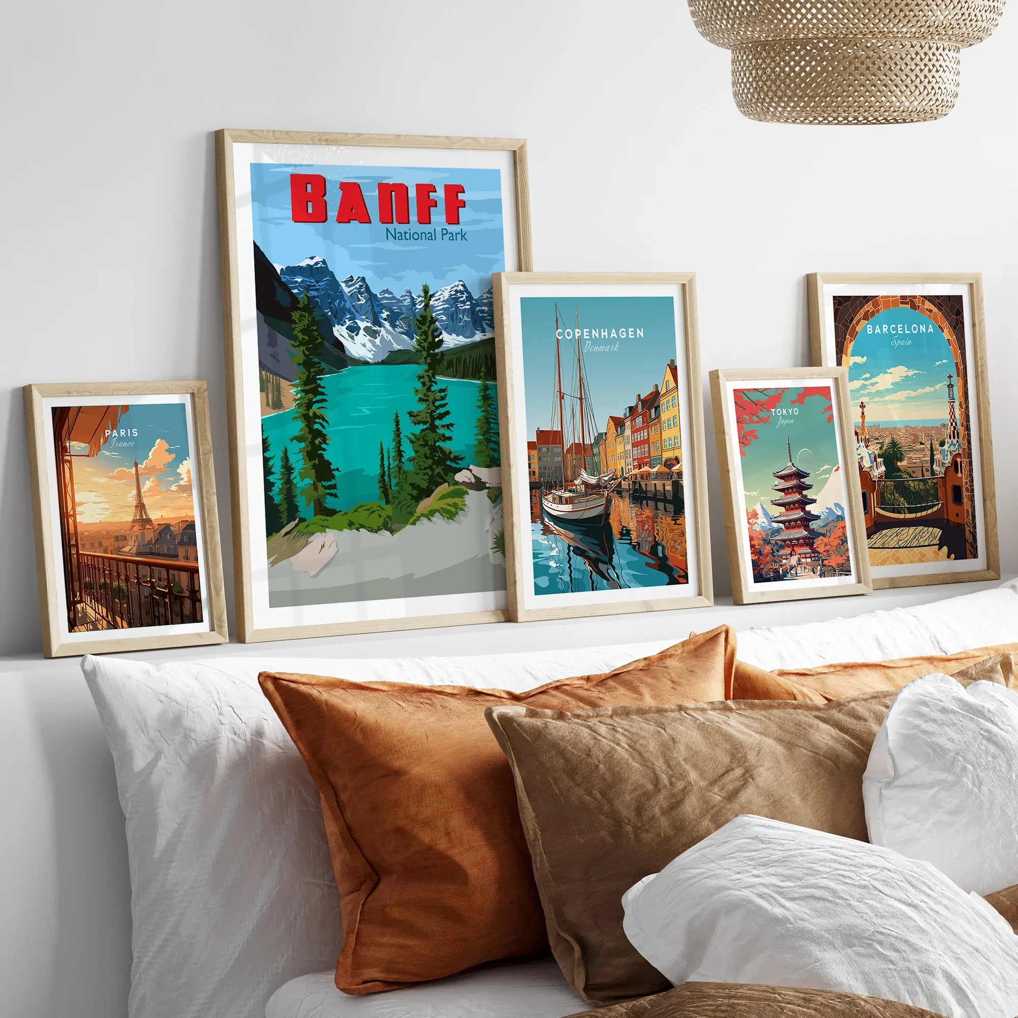 Framed travel posters of Banff, Paris, Copenhagen, Tokyo, and Barcelona above bed with pillows