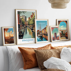 Set of five framed travel posters above a bed, featuring Birmingham, Paris, Copenhagen, Tokyo, Barcelona city art.