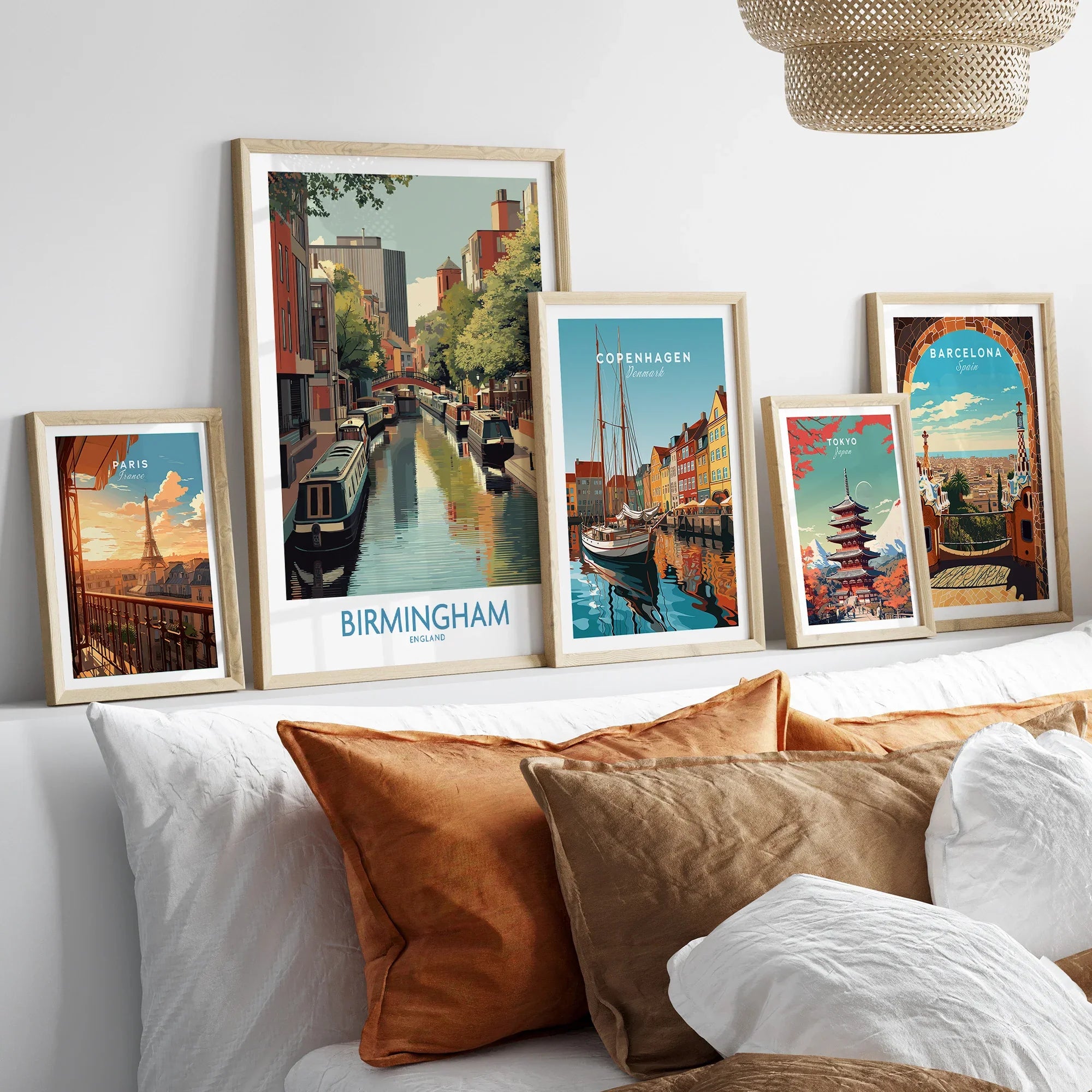 Set of five framed travel posters above a bed, featuring Birmingham, Paris, Copenhagen, Tokyo, Barcelona city art.