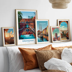 Set of five framed travel posters featuring city skylines above a bed with neutral decor.