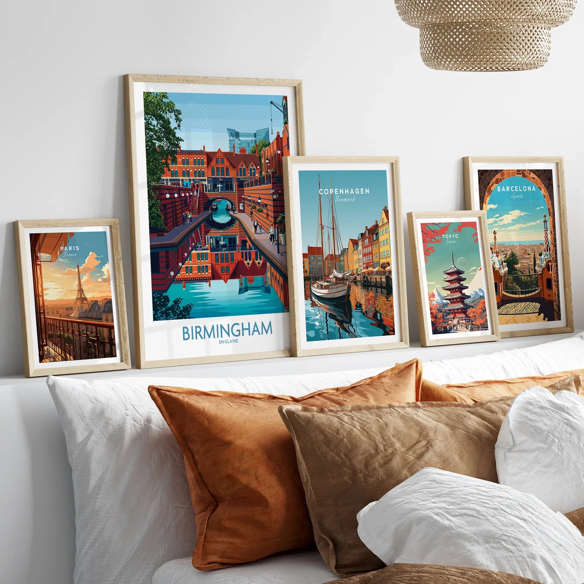 Set of five framed travel posters featuring city skylines above a bed with neutral decor.
