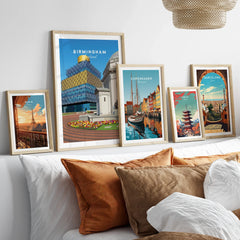 Framed travel posters of Birmingham, Paris, Copenhagen, Tokyo, and Barcelona above a bed