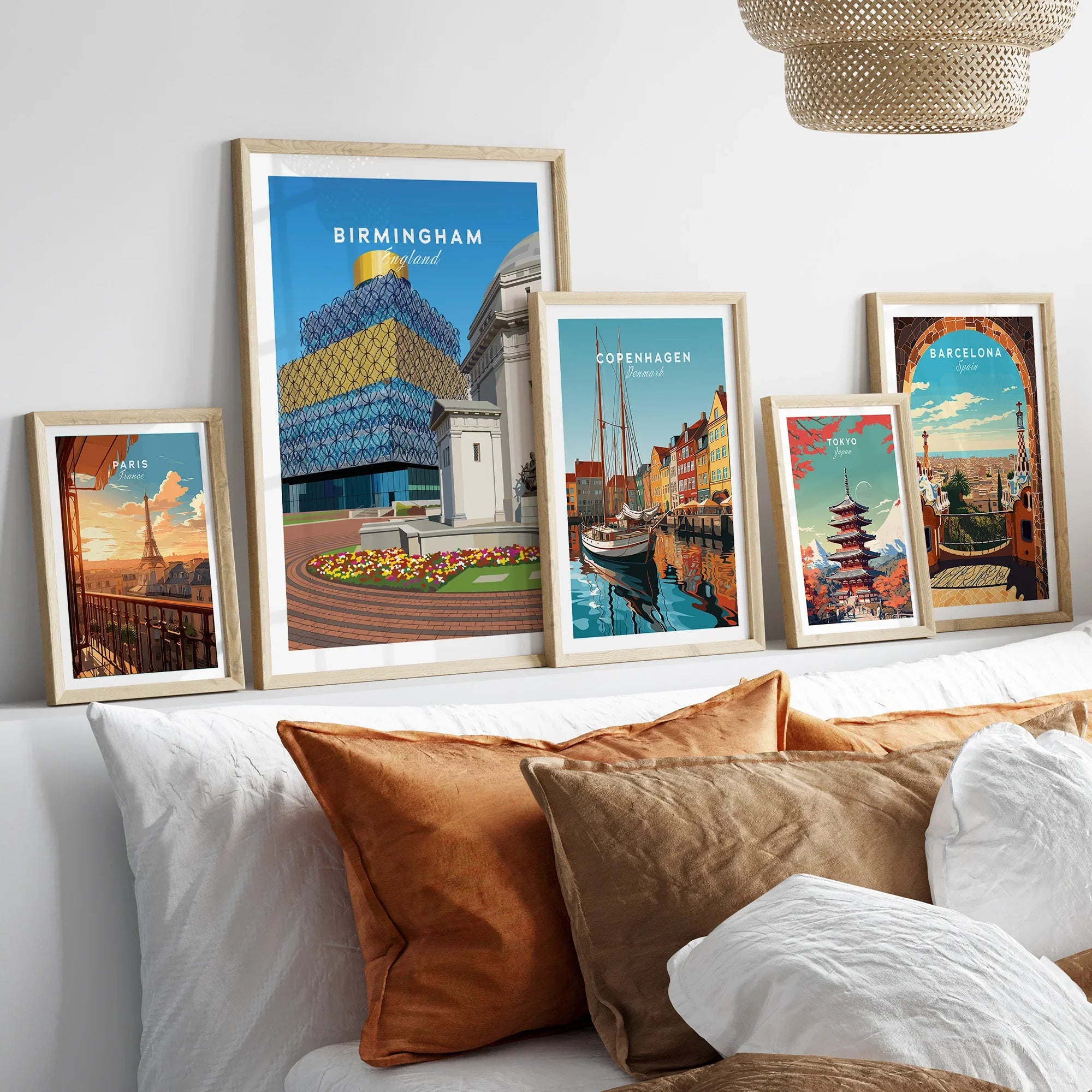 Framed travel posters of Birmingham, Paris, Copenhagen, Tokyo, and Barcelona above a bed