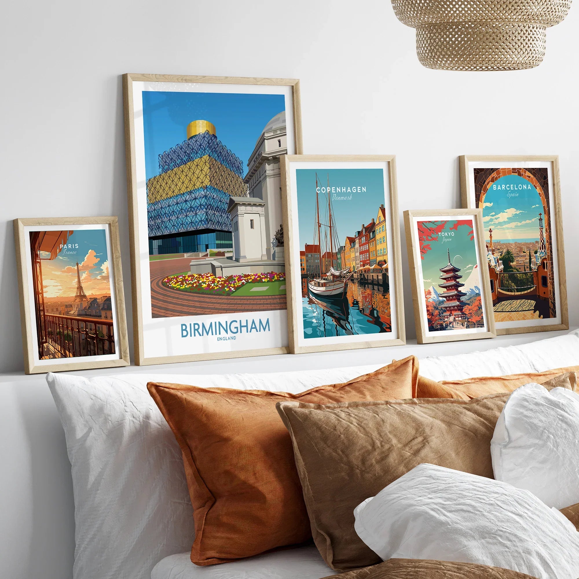 Framed travel posters of Birmingham, Paris, Copenhagen, Tokyo, and Barcelona above a bed