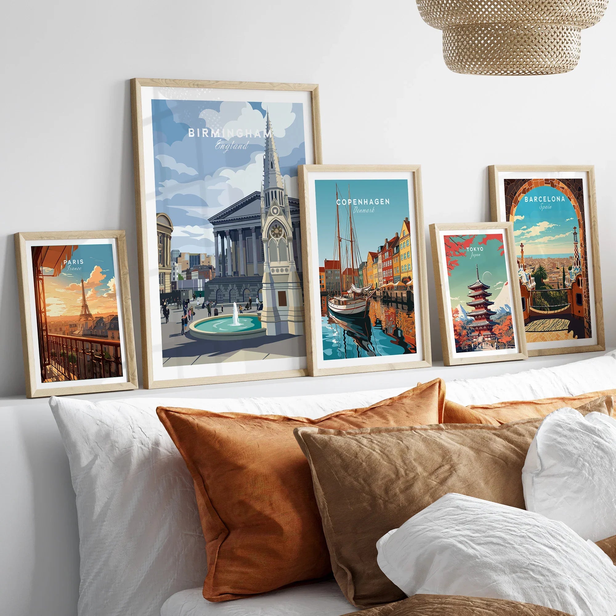 Five framed travel posters of world cities and landmarks above a modern bed with brown pillows.
