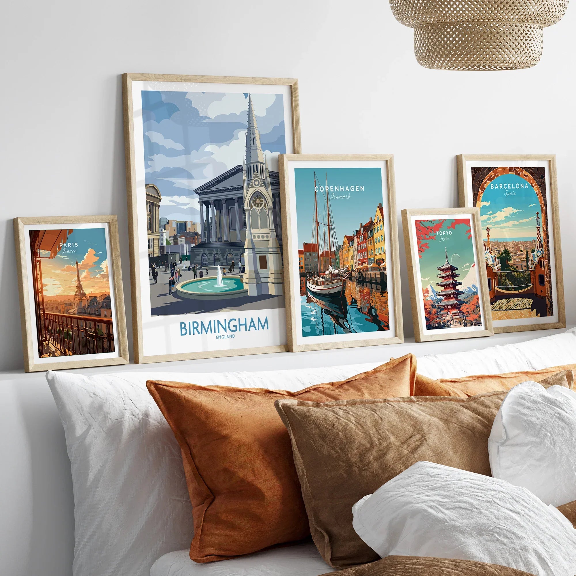 Set of five travel art prints in natural wood frames above bed, featuring city skylines and landmarks.
