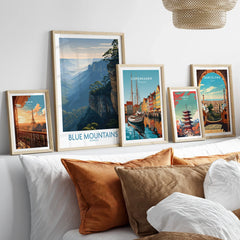 Framed travel posters of Paris, Blue Mountains, Copenhagen, Tokyo, and Barcelona above a bed.