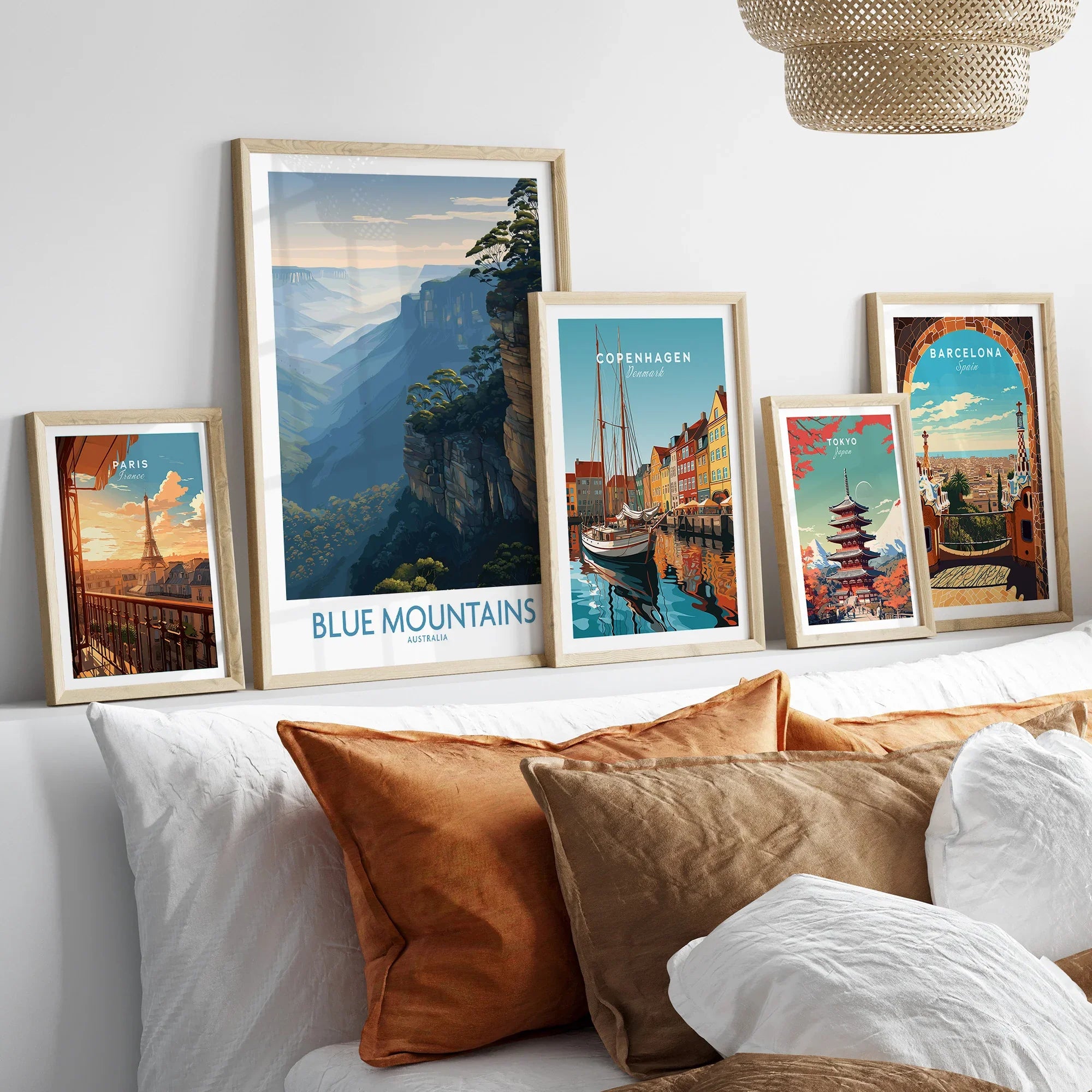 Framed travel posters of Paris, Blue Mountains, Copenhagen, Tokyo, and Barcelona above a bed.