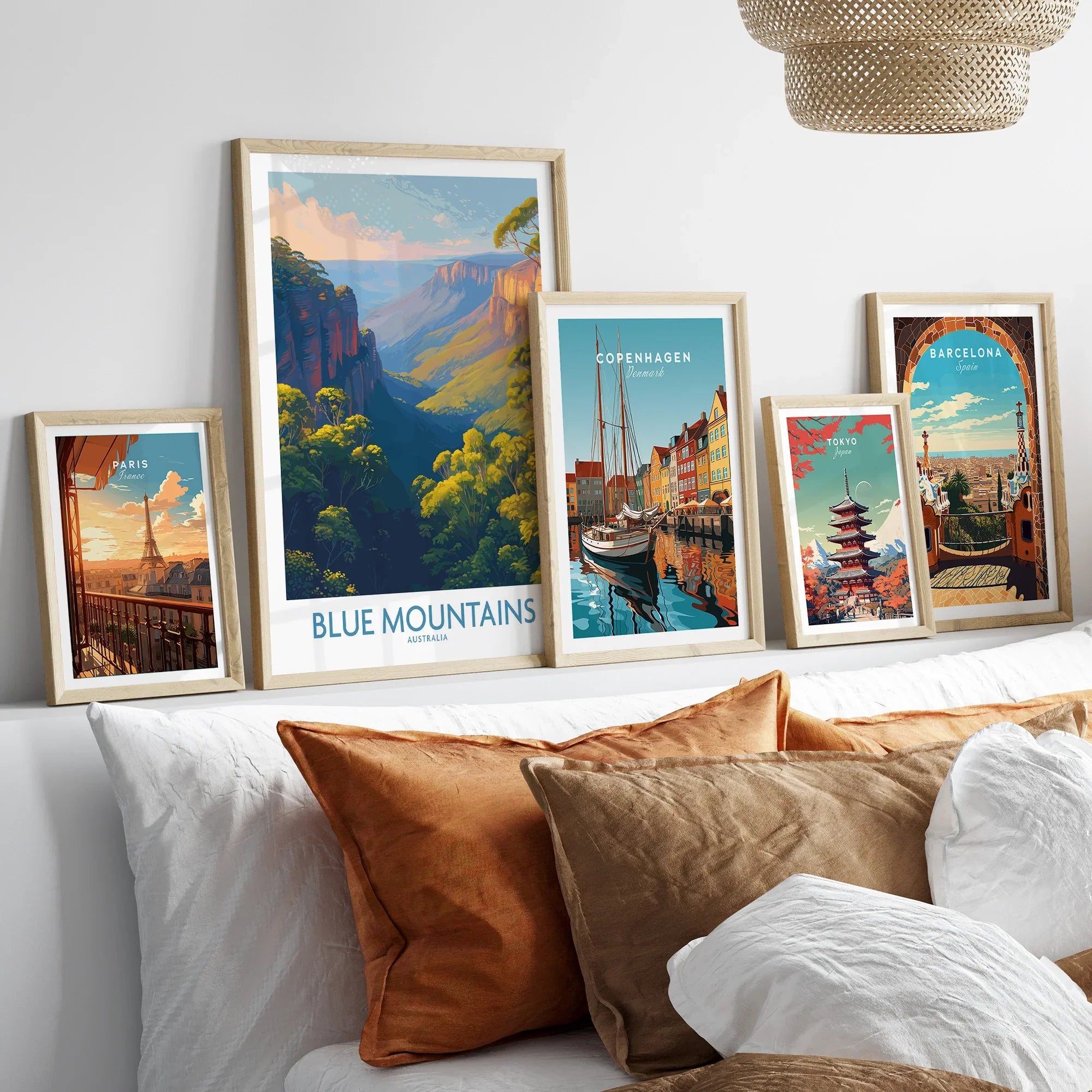 Set of five framed travel posters above bed, featuring Blue Mountains, Paris, Copenhagen, Tokyo, and Barcelona.