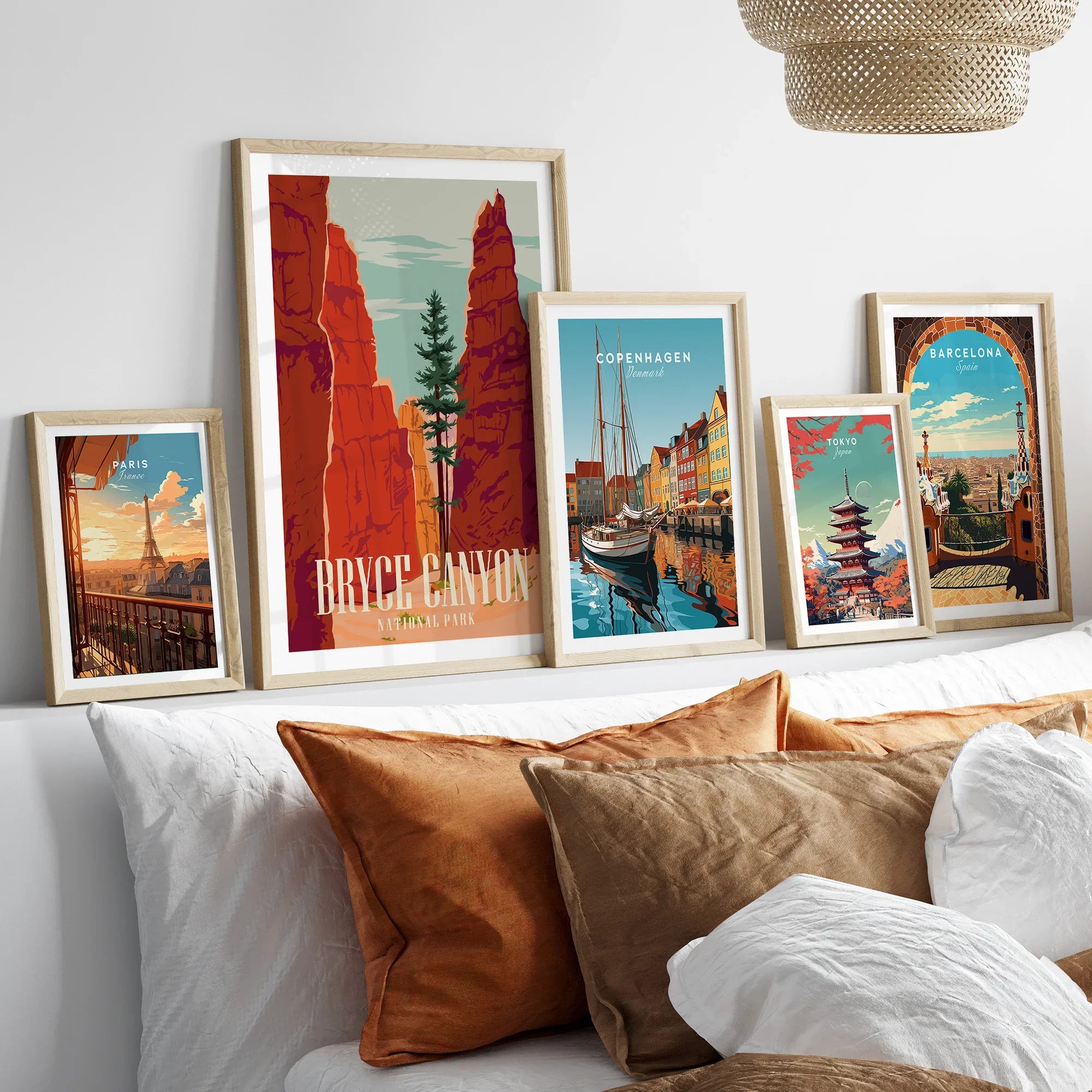 Set of five framed travel and national park art prints above a bed with neutral wood frames.