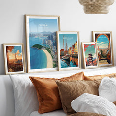 Framed travel posters of Paris, Busan, Copenhagen, Tokyo, and Barcelona above bed