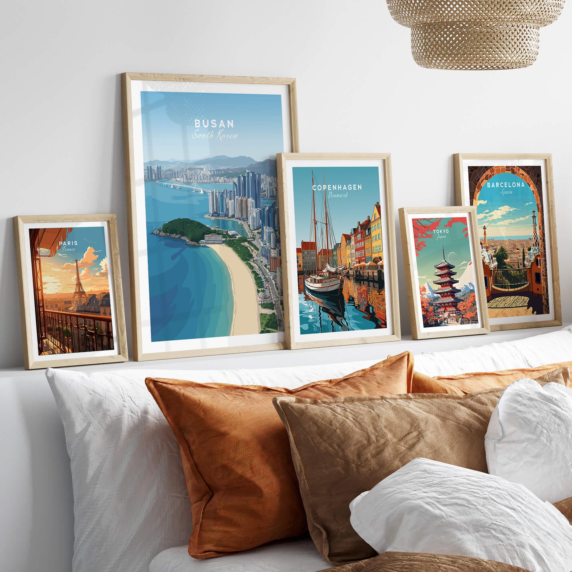 Framed travel posters of Paris, Busan, Copenhagen, Tokyo, and Barcelona above bed