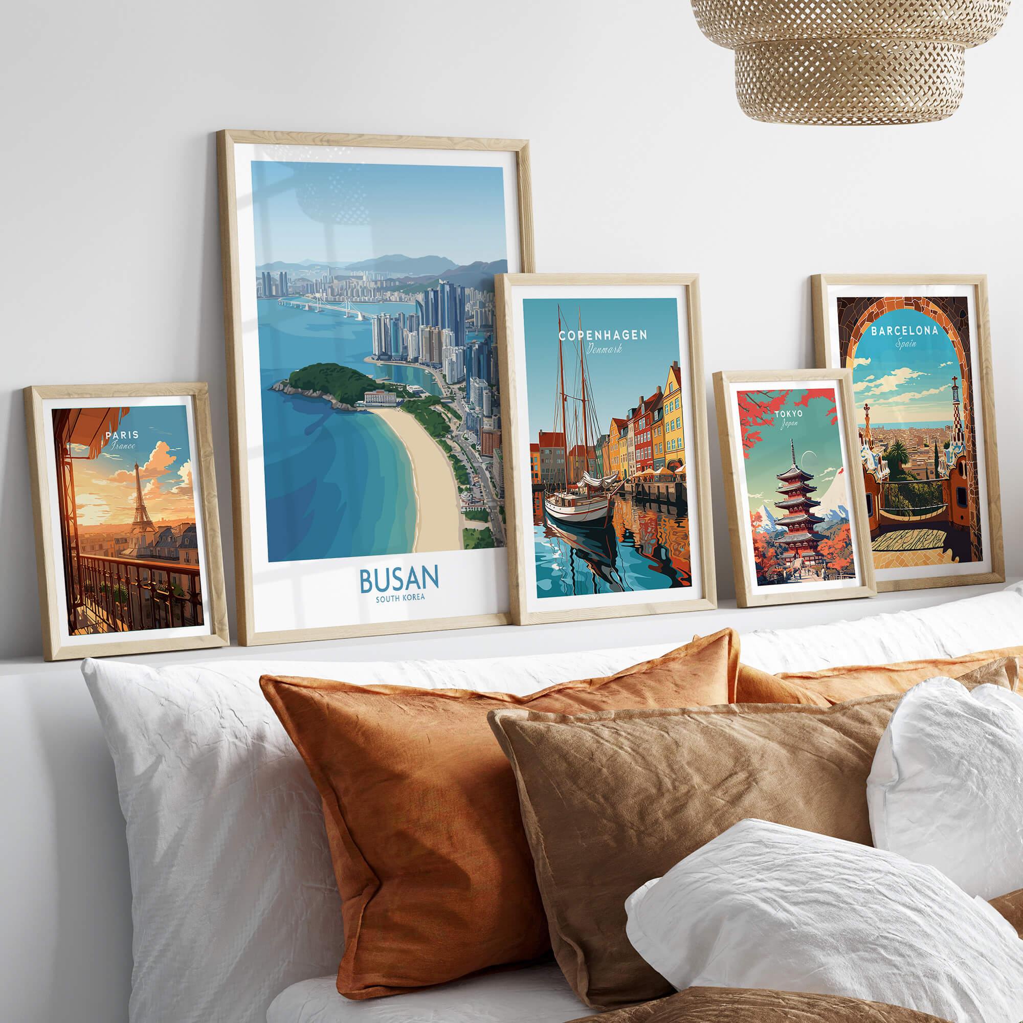 Framed travel poster art prints of Paris, Busan, Copenhagen, Tokyo, and Barcelona above a bed